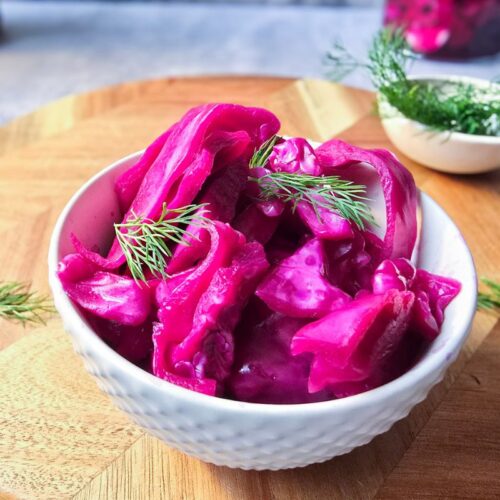 Bowl of pink sauerkraut made from chunks of naturally fermented red cabbage, topped with fresh dill.