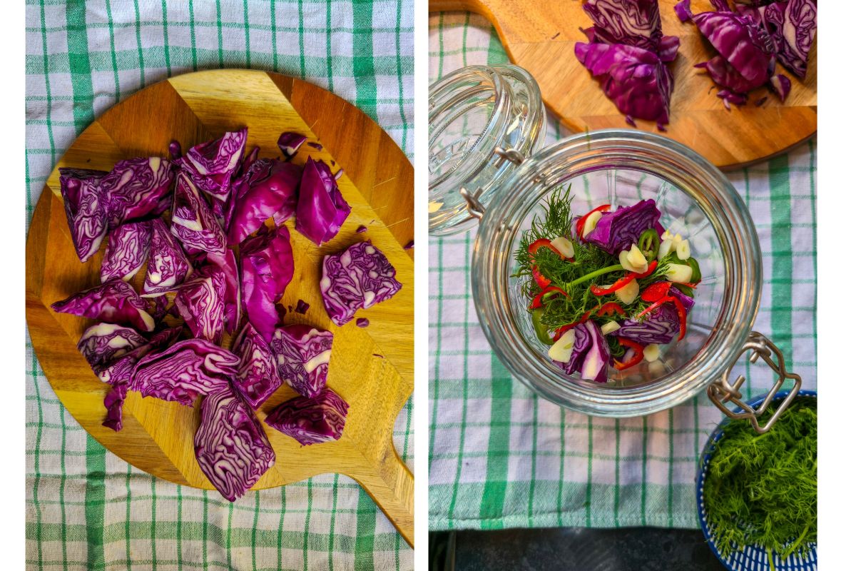 Red cabbage cut into large chunks on a wooden board, and a glass jar layered with dill, sliced garlic, chili and red cabbage.