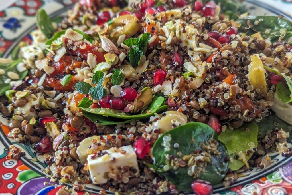 A salad made with quinoa olives roast peppers feta nuts and herbs