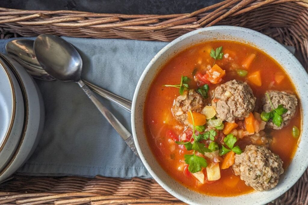 Romanian soup with meatballs in bowl in basket on blue towel