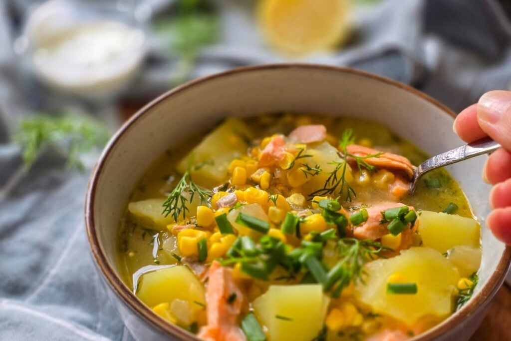 A bowl full of corn and potato chowder with flakes of trout and dill