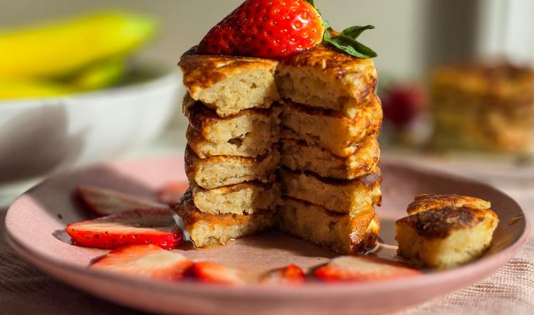 Sourdough Banana Pancakes on pink plate with syrup and strawberry slices