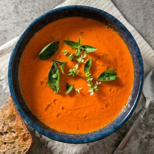 Tomato Soup in Soup Maker, silky roasted tomato soup in a blue bowl with basil and olive oil, served with sourdough toast.