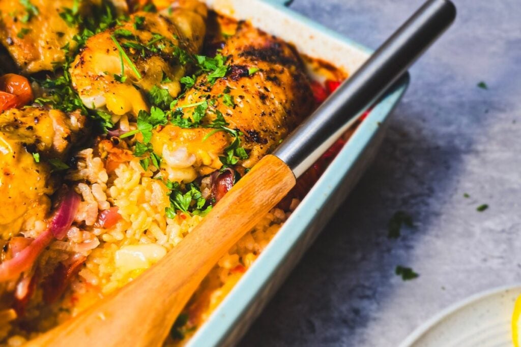 Portuguese-inspired peri peri chicken and rice traybake with peppers, onions, cherry tomatoes and parsley.