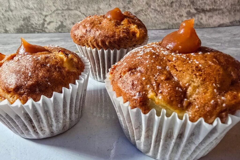 Apple sourdough muffins topped with small apple-butter dollops and a light dusting of icing sugar.
