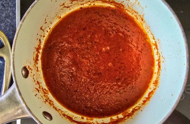 Marinara-style pizza sauce simmering in a small saucepan.