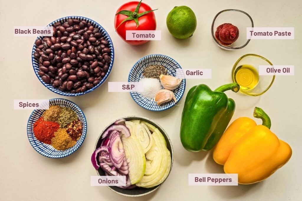 Ingredients for black bean fajitas including black beans, bell peppers, onions, tomato, tomato paste, garlic, olive oil, and spices.