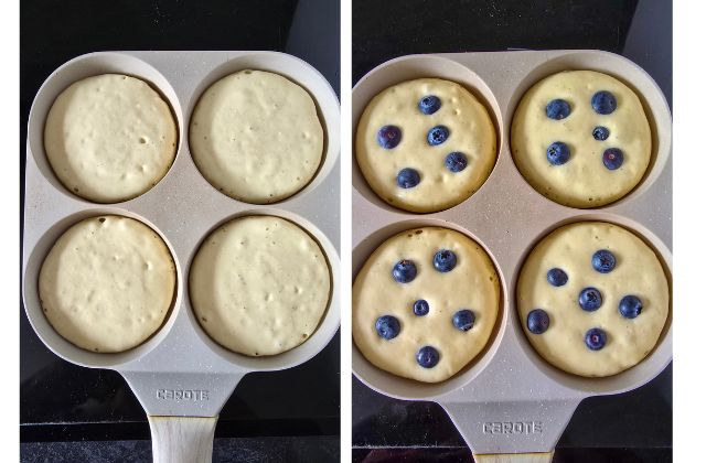 Pancake batter cooking in a four-hole pan, then blueberries studded into the tops before flipping