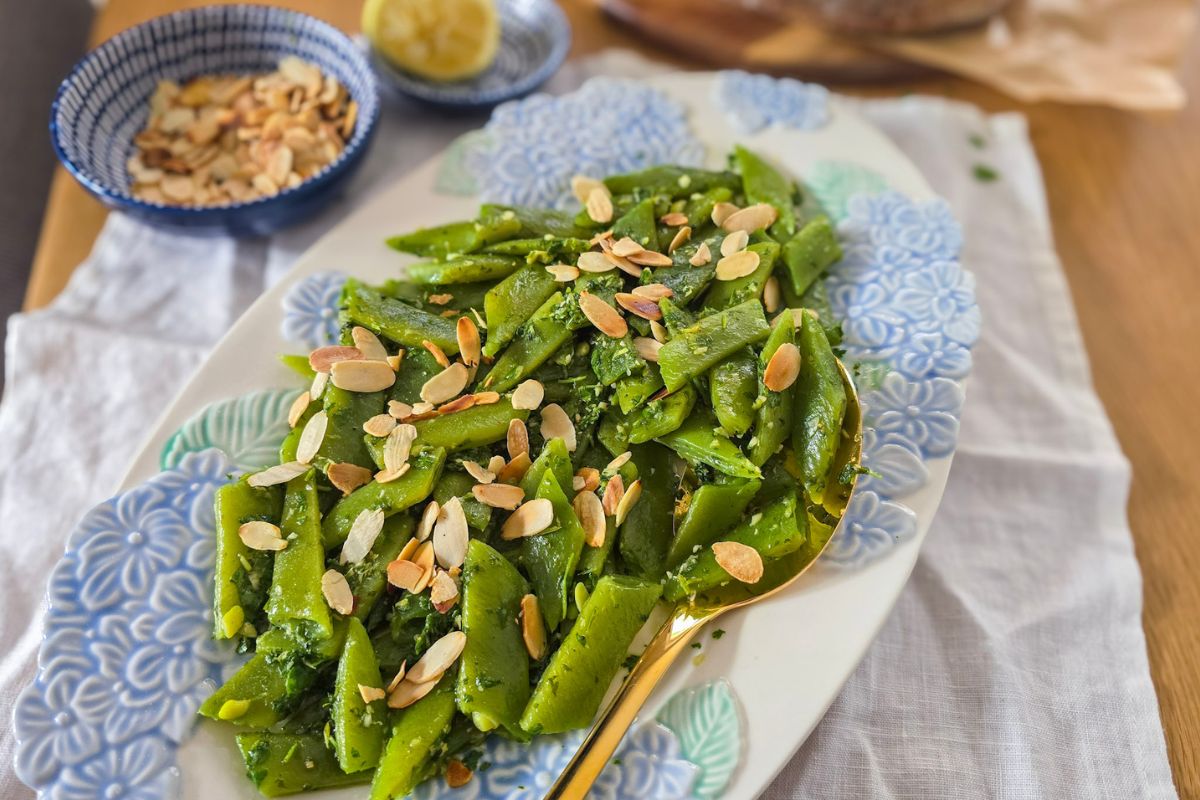 Runner bean salad with gremolata and toasted flaked almonds on a white serving plate