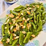 Runner bean salad with gremolata and toasted flaked almonds on a white serving plate