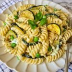 Fusilli pasta with caramelized zucchini, peas, and whipped feta sauce garnished with basil and mint
