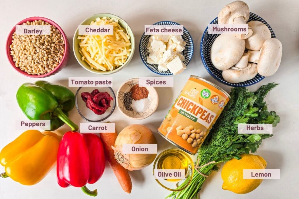 ingredients for barley stuffed peppers, including barley, peppers, mushrooms, chickpeas, feta, cheddar, and herbs.